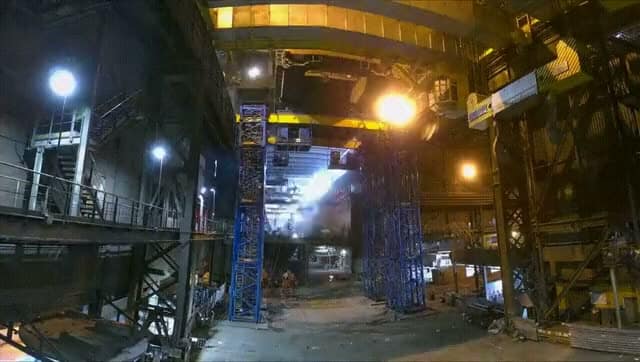 Temporary support structure erected inside the industrial building at night, with an elevated walkway and work lighting