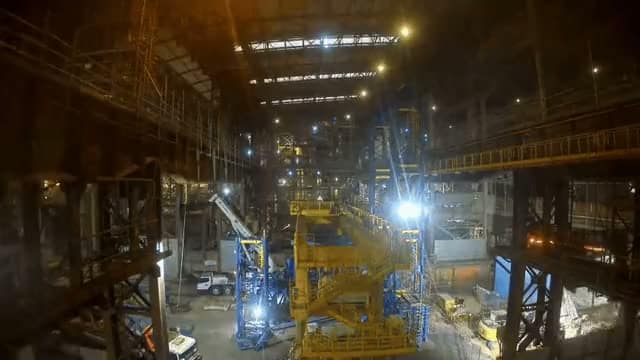 Wide view of the same temporary support structure during erection, with equipment and crew working inside the building