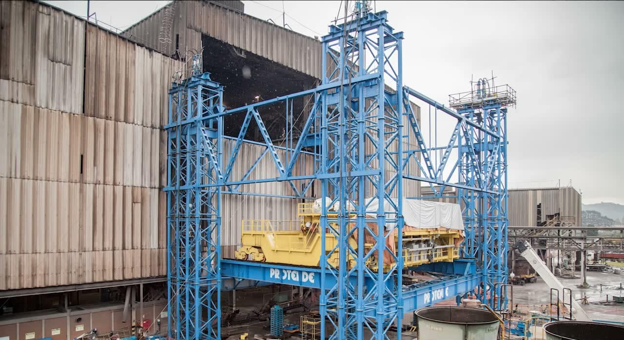 Time-lapse of an overhead crane being lifted between two steel lifting towers in a steel plant, from day into night